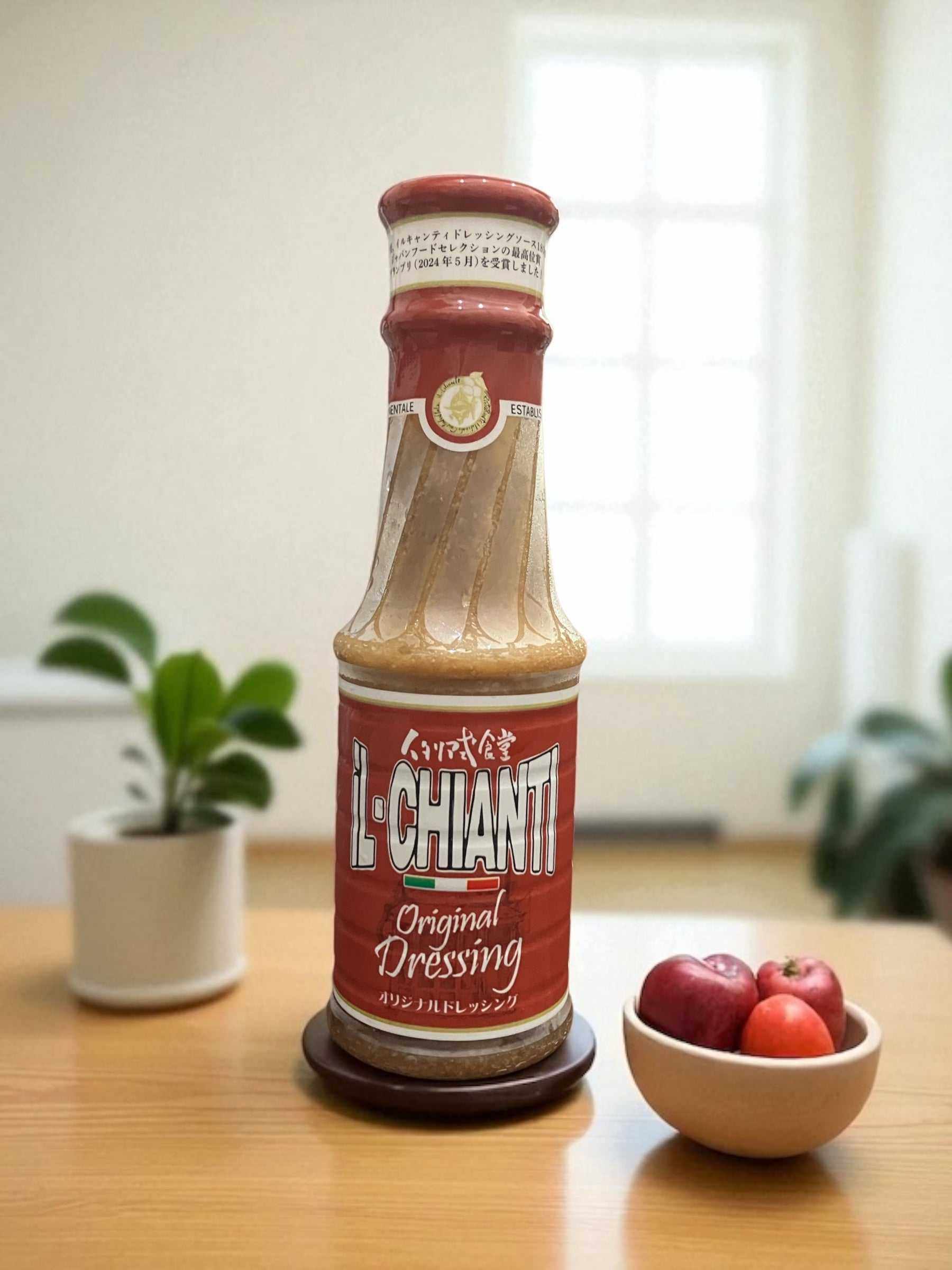 Bottle of Il Chianti Original Dressing 380g on wooden table with plants and fruit bowl in background